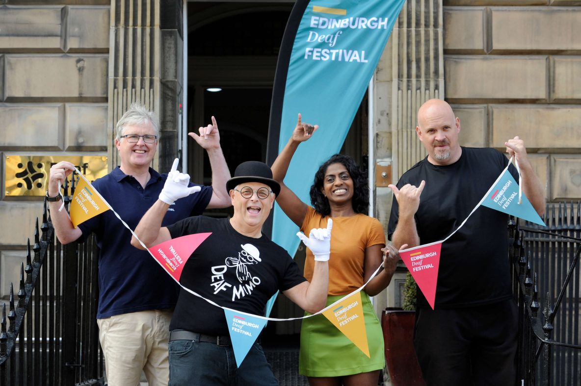 Five people standing holding Edinburgh deaf festival bunting